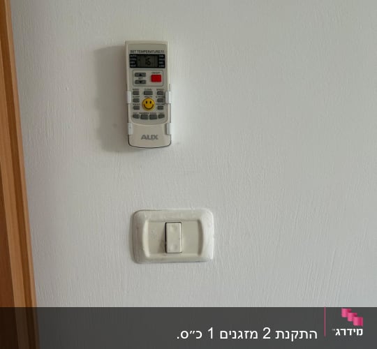 שלט רחוק למזגן תלוי על קיר לבן
